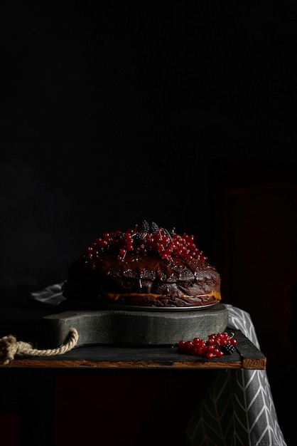 Een zwarte cake met rode bessen erop