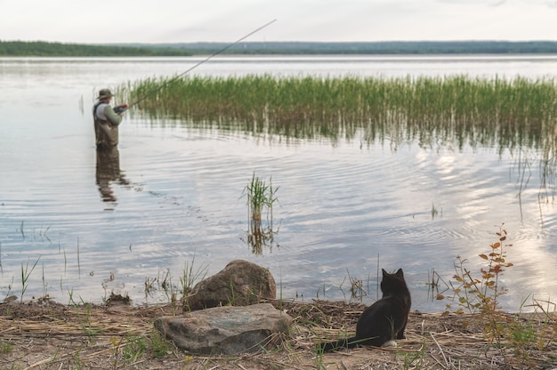 Foto een zwarte kat zit aan de kust en wacht op de gevangen vis van de visser