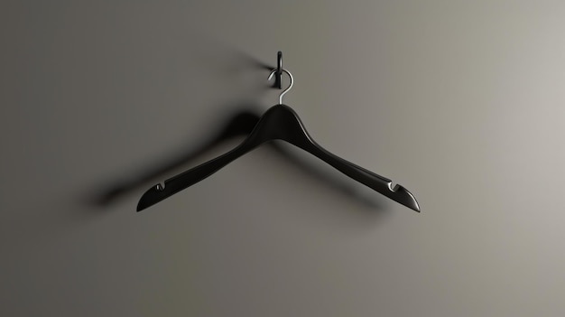 Foto een zwarte kledinghanger hangt aan een grijze muur de hanger is gemaakt van plastic en heeft een haak aan de bovenkant de hangers is leeg en wacht om gebruikt te worden