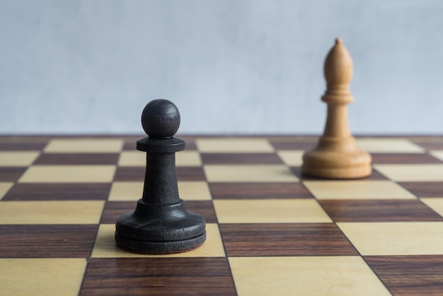 Een zwarte pion achtervolgd door een witte loper op het schaakbord