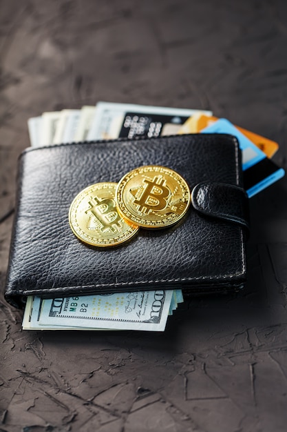 Een zwarte portemonnee met dollars, e-cards en bitcoins op zwart getextureerd.