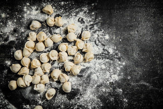 Een zwarte tafel met meel en pasta erop