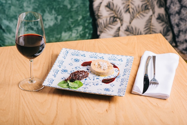 Foto eendenlever met saus op een houten tafel en een glas wijn