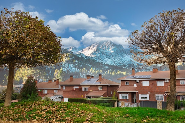 Eengezinswoningen met zonnepanelen op het dak met onderaan hoge bergen.