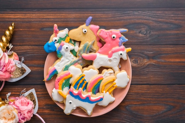 Eenhoornvormige suikerkoekjes versierd door kinderen met royal icing op roze bord.