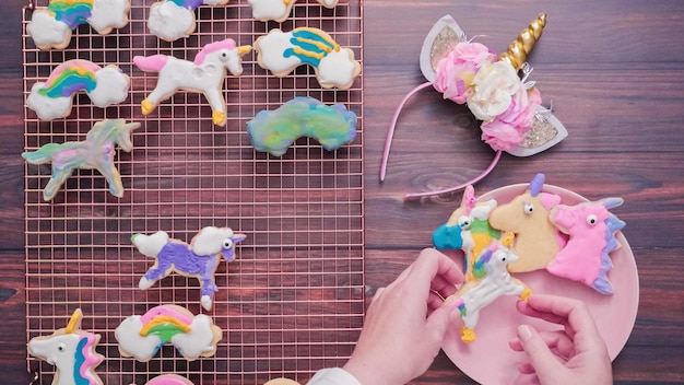 Eenhoornvormige suikerkoekjes versierd met royal icing op roze bord.