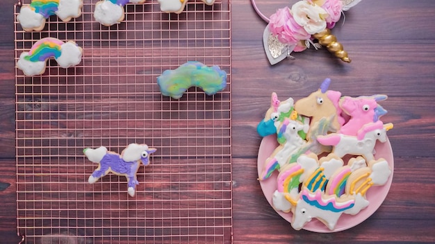 Eenhoornvormige suikerkoekjes versierd met royal icing op roze bord.