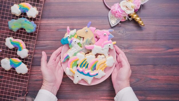 Eenhoornvormige suikerkoekjes versierd met royal icing op roze bord.