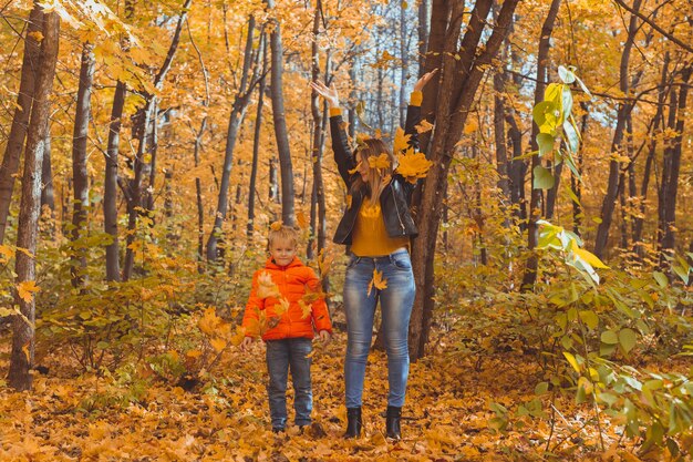 Eenoudergezin spelen met herfstbladeren in het park. Gelukkige moeder en zoon gooien herfstbladeren in het herfstpark.