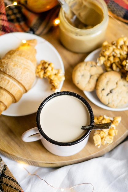 Eenvoudig landhuisontbijt op bed koffie met melk en huisgemaakt gebak op geruite deken