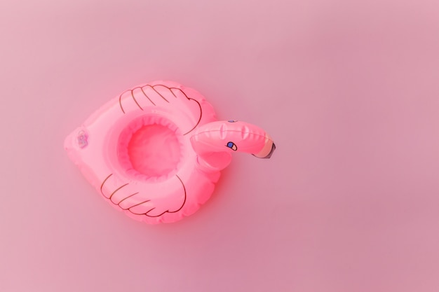 Eenvoudig minimaal ontwerp met opblaasbare flamingo geïsoleerd op pastelroze achtergrond.