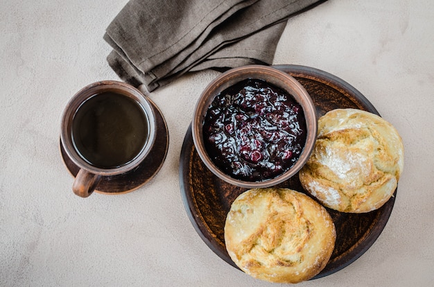 Eenvoudig ontbijt: koffie americano, verse broodjes en jam.