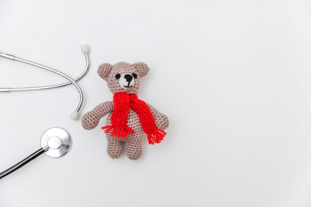 Foto eenvoudig ontwerp speelgoed beer en geneeskunde apparatuur stethoscoop geïsoleerd op een wit oppervlak. gezondheidszorg kinderen arts concept. kinderarts symbool. plat lag, bovenaanzicht kopie ruimte