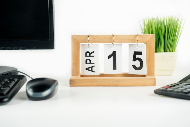 Eenvoudige bureaukalender voor april met datum 15 op tafel met computerdesktop