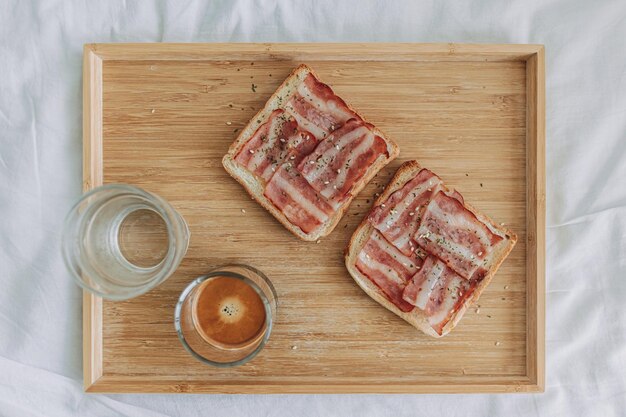 Eenvoudige eenvoudige ontbijtset van Bacon Sandwich geserveerd met zwarte koffie op bed