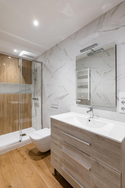 Eenvoudige en moderne badkamer met marmeren witte tegels houten afwerking toilet en douche