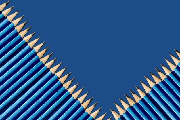 Eenvoudige potloden in het blauw op een blauwe achtergrond. Potloden liggen schuin. Achtergrond van blauwe klassieke kleur.