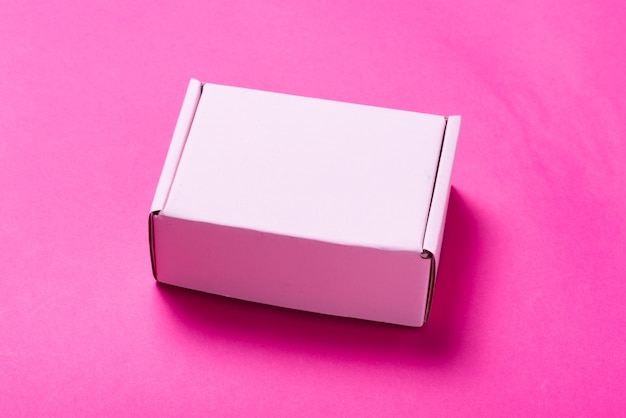 Foto eenvoudige roze kartonnen doos op gekleurde achtergrond, geopend, leeg van binnen