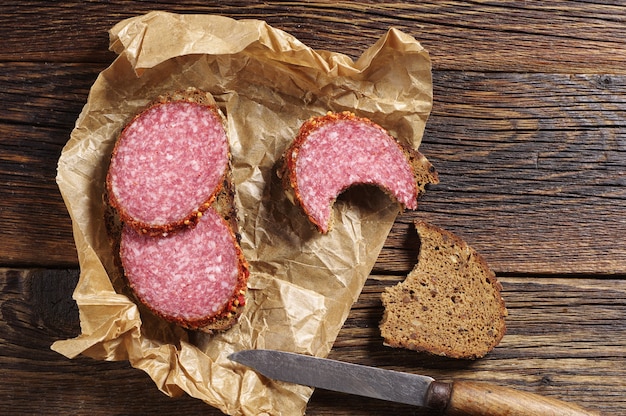 Eenvoudige sandwich met salami en roggebrood op keukenbord, bovenaanzicht