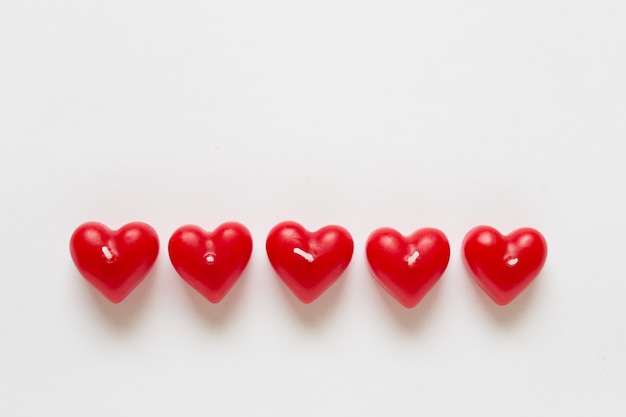 Eenvoudige Valentijnsdag oppervlak met veel rode hartvormige kaarsen op een witte ondergrond. Foto met lege exemplaarruimte.