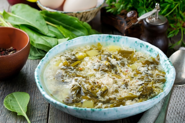 Eenvoudige vegetarische soep gemaakt van zuring, aardappelen en losgeklopte eieren op een oude houten ondergrond