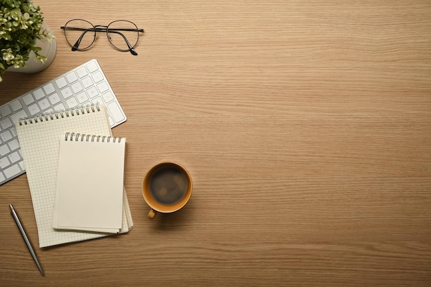 Eenvoudige werkplek met notebooks brillen toetsenbord en koffiekopje op houten bureau