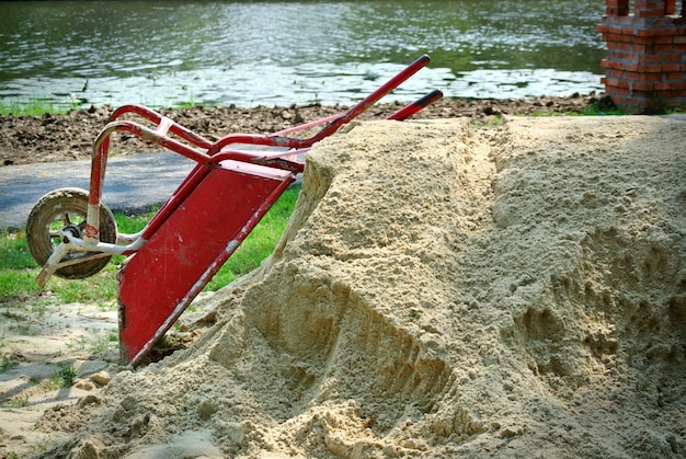 Eenwielige rode bouwkar op een stapel zand