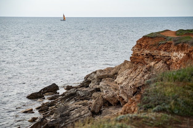 Eenzaam jacht op de lege stenen kust in volle zee