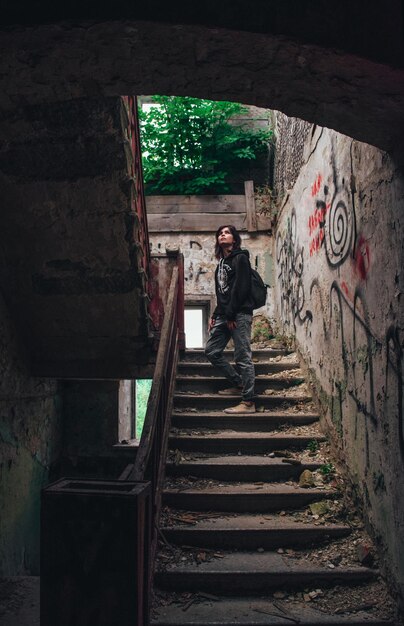 Eenzaam meisje in een verlaten huis dat naar het licht gaat op de verwoeste trap tijdens de post-apocalyps