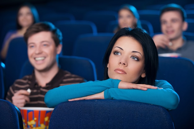 Eenzaam voelen in de bioscoop. Verveelde jonge vrouw die naar film kijkt in de bioscoop