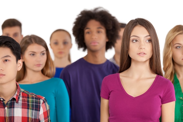 Foto eenzaamheid in een menigte. gefrustreerde jonge vrouw die onder een multi-etnische groep mensen staat en wegkijkt