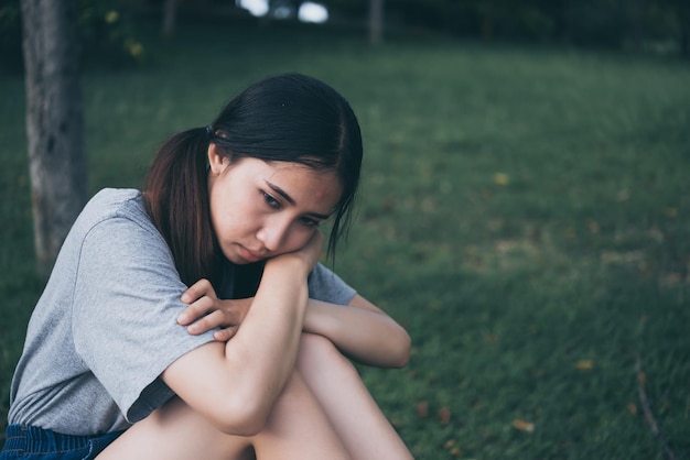 Eenzame Aziatische vrouw zit alleen in het park Trieste Thaise vrouw denkt iets Hartverscheurend meisje concept