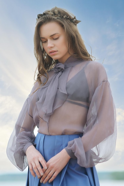 Eenzame jonge vrouw op het strand in blauwe rok en transparante blouse