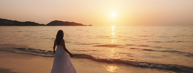 Eenzame jonge vrouw wandelen en genieten van de prachtige zonsondergang op het rustige strand Reizen op zomervakantie concept Banner panorama