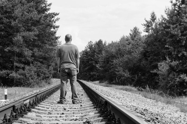 Eenzame man lopen op een spoorlijn zwart-wit tone