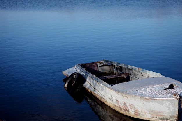 Eenzame roeiboot bij meer met blauw water. Ruimte kopiëren