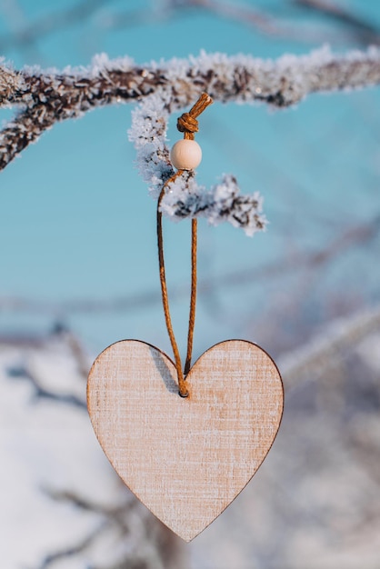 Eenzame valentijn houten hart op ijzige ijzige tak in besneeuwde bos wenskaart voor valentijnsdag ...