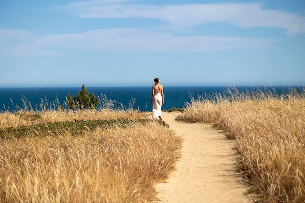 Eenzame vrouw langs een onverharde weg die naar de horizon kijkt bij een klif in de Algarve, Portugal