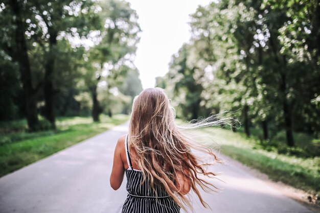 eenzame vrouw loopt langs de weg door het bos om in de zomer nieuw leven te ontmoeten
