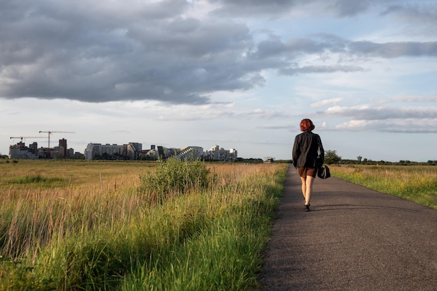 Eenzame vrouw loopt langs een lege weg aan de rand