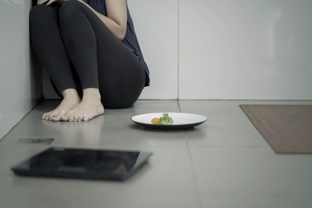 Foto eenzame vrouw met salade en weegschaal.