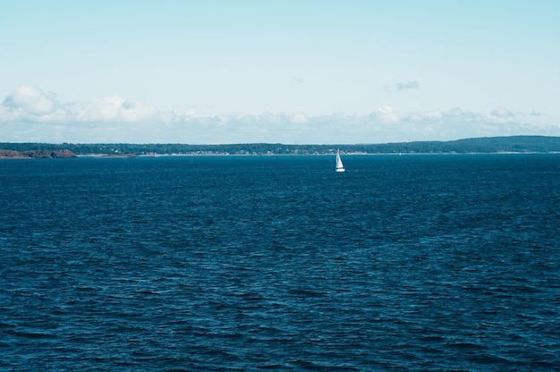 Foto eenzame witte zeilboot die op vreedzaam en kalm water van mos vaart
