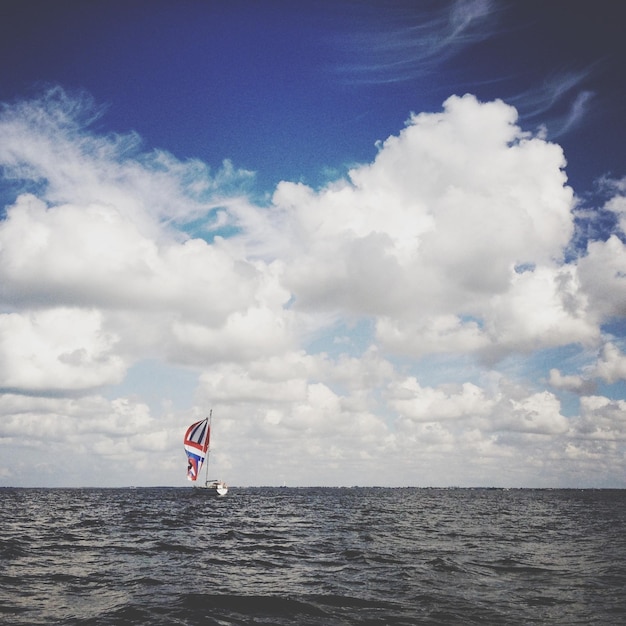 Foto eenzame zeilboot in de verte in rustige zee tegen de lucht