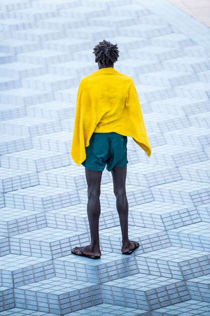 Eenzame zwarte Afrikaanse man, in vrede met een handdoek na het verlaten van het strand in een stedelijke omgeving