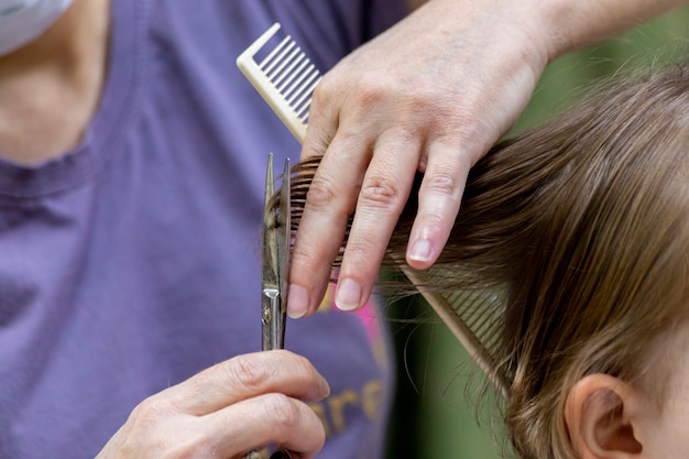 Foto eerste knipbeurt voor een jong meisje. gespleten haarpunten knippen met een schaar.