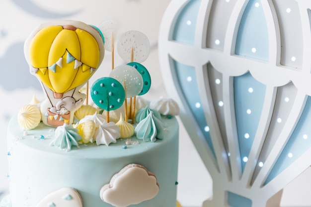 Eerste verjaardagstaart voor kinderen, blauwe cake met wolken, meringue en ballonnen