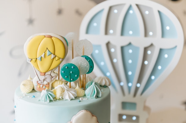 Eerste verjaardagstaart voor kinderen, blauwe cake met wolken, meringue en ballonnen