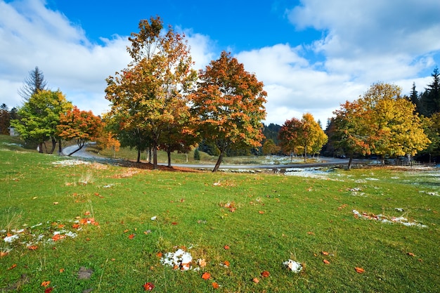 Eerste wintersneeuw en herfst kleurrijk gebladerte in de buurt van secundaire bergweg (Karpaten, Oekraïne)