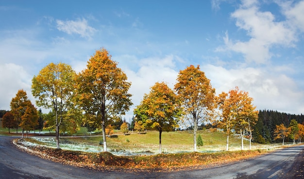 Eerste wintersneeuw en kleurrijke herfstbomen in de buurt van de bergweg