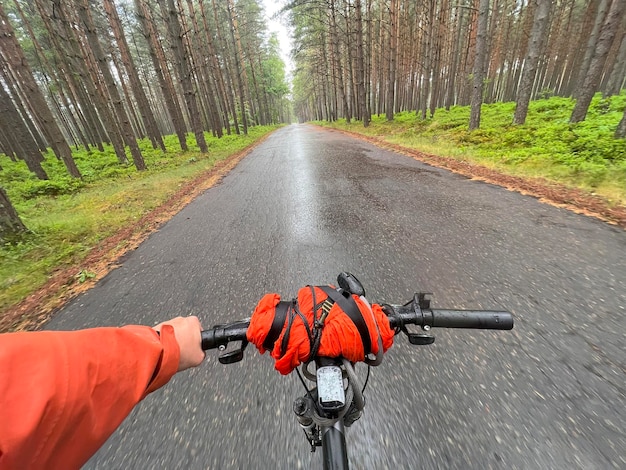 Eerstepersoonsbeeld van het hanteren van de fiets op de bosweg in de stad naar het zonlicht Concept van het gebruik van een fiets voor sport en recreatie buiten de stad